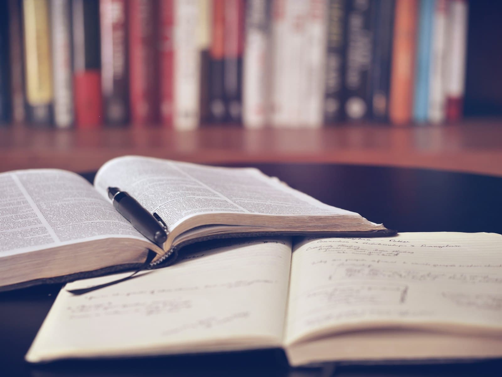دفترچه و دیکشنری باز کنار هم؛ استفاده از زیرنویس انگلیسی برای یادگیری زبان